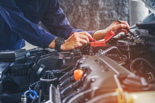 An auto mechanic testing a car's battery