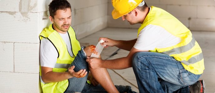 A coworker tends to a construction worker's injured knee
