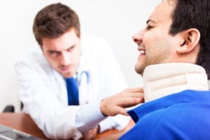 A doctor checks the alignment of a brace holding a victim's neck still