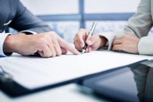 An attorney shows a victim where to sign a settlement agreement