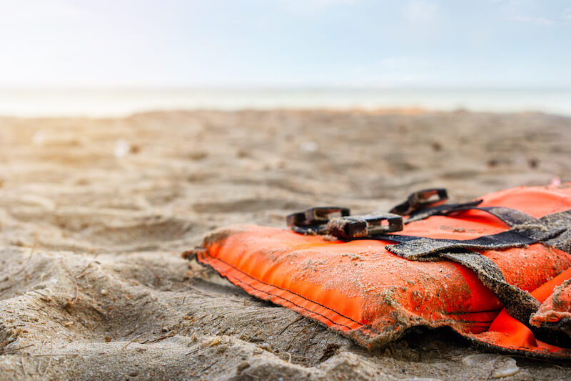 A lifejacket lays left behind on a beach.