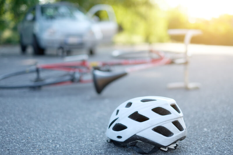 Un casco de bicicleta en la calle cerca de una bicicleta que fue atropellada por un automóvil