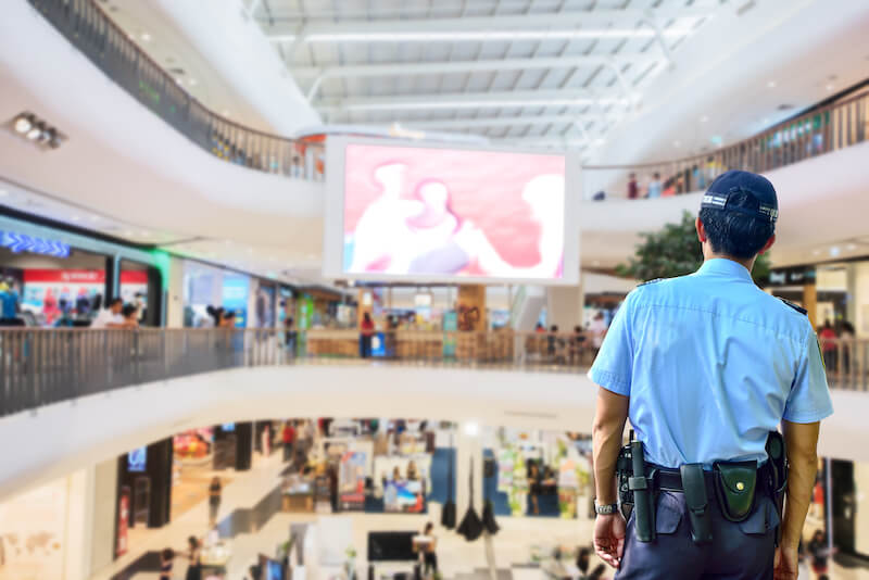Un guardia de seguridad se encuentra en una posición estratégica para ver tres niveles en un centro comercial.