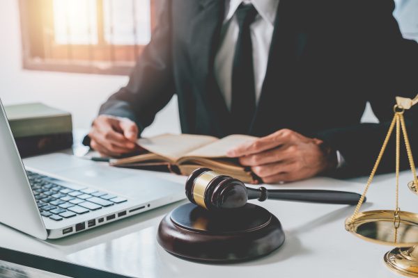 Un abogado sentado en su escritorio con mazo, balanza legal y computadora.