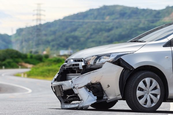 A car with its front bumper hanging off due to an accident.