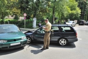 A police officer is writing a report on a parking lot accident.
