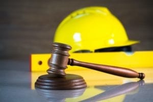 A gavel in front of a hard hat and a level.