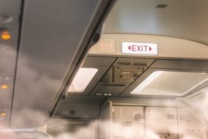 Smoke filling up a plane near the exit sign.
