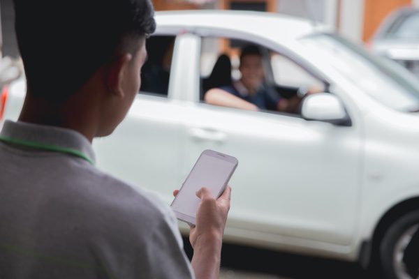 A man calling for an Uber or a Lyft on his phone.