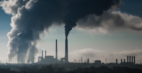  Una imagen de una planta química con humo saliendo de las chimeneas.