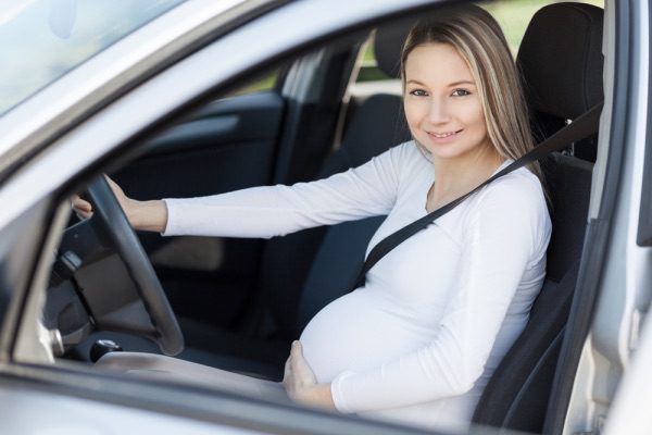 A pregnant woman driving a car.